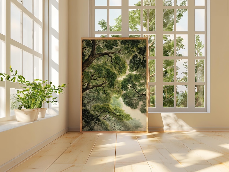 May include: A framed art print of a forest canopy in shades of green and brown. The artwork is displayed in a bright room with a large window overlooking a lush green landscape. Potted plants sit on the windowsill.
