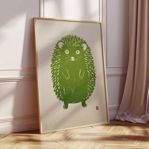Pu&ograve; includere: Una stampa artistica incorniciata con un'illustrazione di un riccio verde. Il riccio &egrave; raffigurato in uno stile linoleografico stilizzato con un aspetto strutturato. L'opera d'arte &egrave; ambientata su uno sfondo color crema e incorniciata in una cornice di legno chiaro.