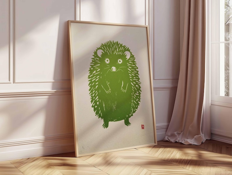 Pu&ograve; includere: Una stampa artistica incorniciata con un'illustrazione di un riccio verde. Il riccio &egrave; raffigurato in uno stile linoleografico stilizzato con un aspetto strutturato. L'opera d'arte &egrave; ambientata su uno sfondo color crema e incorniciata in una cornice di legno chiaro.