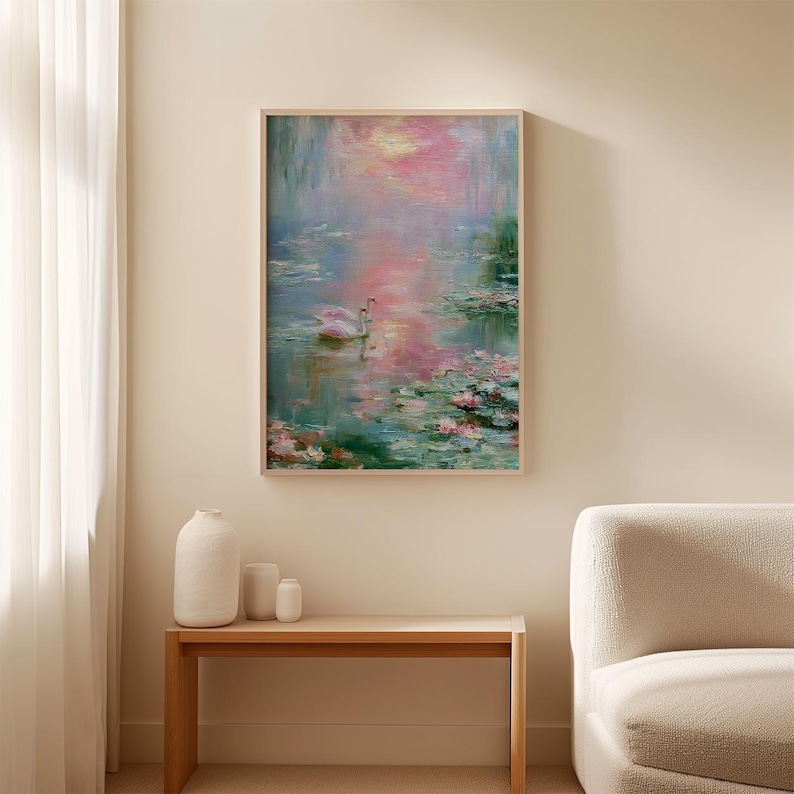 May include: A framed painting depicts a serene water scene with two white swans. The artwork features a soft color palette of pink, blue, and green, with visible brushstrokes. The painting is displayed above a wooden table.