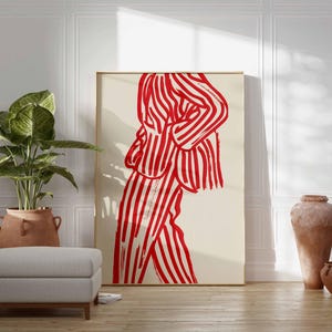 K&ouml;nnte beinhalten: Ein gro&szlig;er gerahmter Kunstdruck mit einer Figur in einem rot-wei&szlig; gestreiften Anzug. Das Kunstwerk wird in einem Raum mit einer Topfpflanze, einem grauen Hocker und Terrakotta-Vasen ausgestellt. Die Gesamt&auml;sthetik ist modern und minimalistisch.