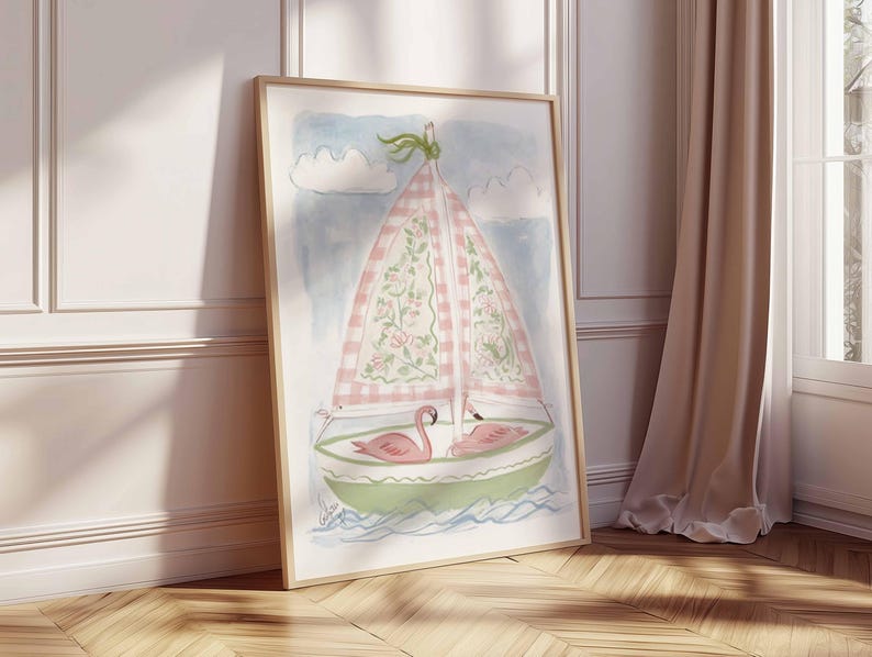 May include: Watercolor painting of a sailboat with a pink and white checkered sail, floral accents, and two pink flamingos. The boat is green and white, set against a blue sky with white clouds. The artwork is framed in a light wood frame.