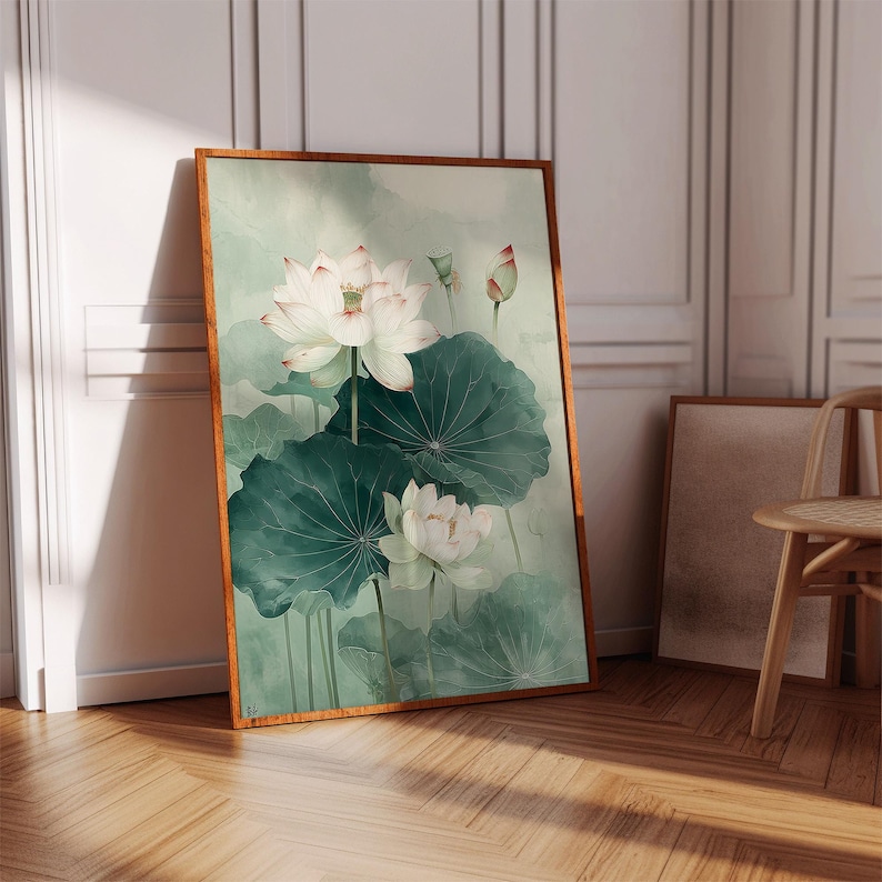 Puede incluir: Una impresi&oacute;n art&iacute;stica enmarcada que presenta una pintura de acuarela de flores de loto blancas con hojas verdes. La obra de arte tiene una paleta de colores suaves y apagados con un fondo verde claro. El marco es de color marr&oacute;n c&aacute;lido.
