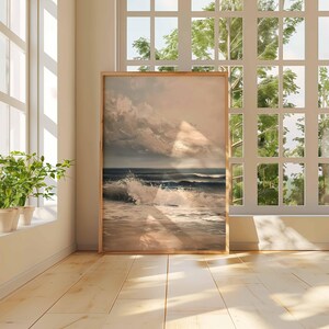 May include: A framed art print of a seascape with crashing waves and a cloudy sky. The artwork is displayed in a room with a large window and natural light. The frame is a light brown color.