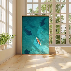 May include: A framed art print depicts an aerial view of a turquoise ocean with dark blue silhouettes of marine life. A white and orange canoe is in the center. The artwork is displayed in a bright room with a window.