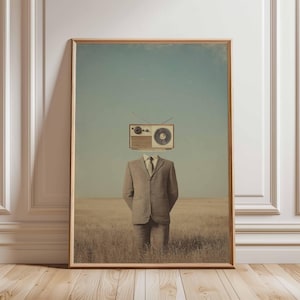 Op de afbeelding: Een ingelijste kunstdruk met een man in een pak met een vintage radio als hoofd, staand in een veld. Het kunstwerk heeft een surrealistische, vintage esthetiek met een gedempt kleurenpalet van beige, bruin en blauw.