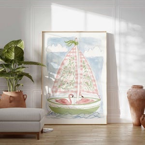 May include: Watercolor painting of a sailboat with a pink and white checkered sail, floral details, and two pink flamingos. The artwork is framed and leans against a white wall. A large potted plant, a gray ottoman, and terracotta vases are in the foreground.
