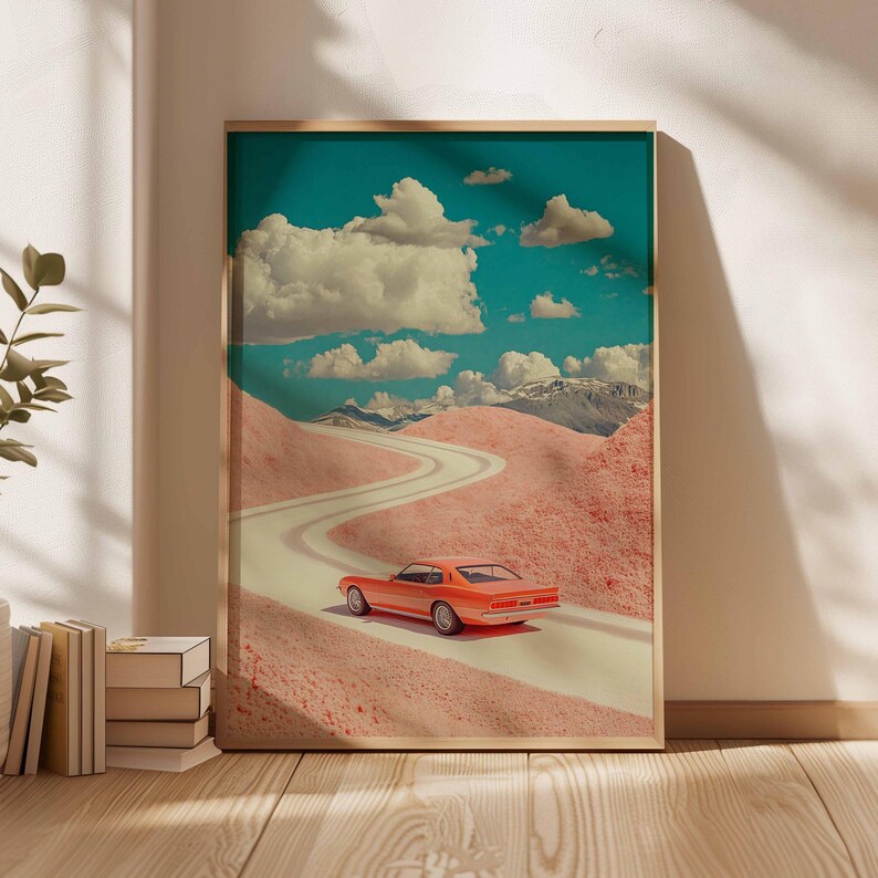K&ouml;nnte beinhalten: Gerahmter Kunstdruck mit einem orangefarbenen Auto auf einer kurvenreichen Stra&szlig;e durch rosa H&uuml;gel unter blauem Himmel mit Wolken. Das Kunstwerk hat eine Retro-&Auml;sthetik, mit schneebedeckten Bergen im Hintergrund. Holzrahmen.