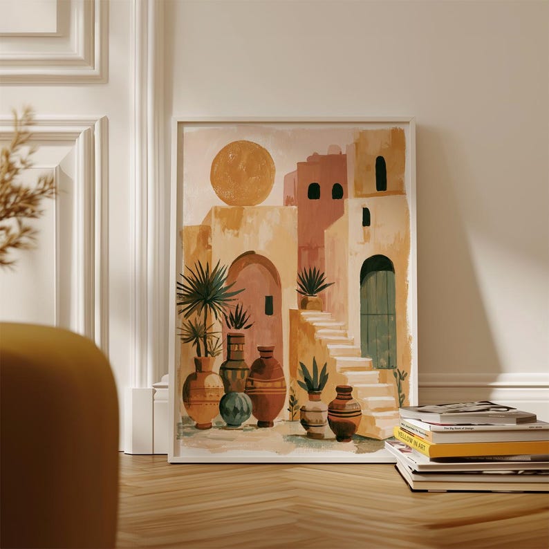 Peut inclure: Une impression d'art encadr&eacute;e repr&eacute;sentant une sc&egrave;ne de d&eacute;sert avec des b&acirc;timents aux tons p&ecirc;che, beige et marron. L'&oelig;uvre pr&eacute;sente un grand soleil, des escaliers, des arches et des vases d&eacute;coratifs avec des plantes. L'impression est expos&eacute;e sur un sol en bois.