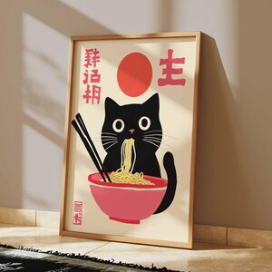 May include: A black cat with big eyes is eating ramen noodles from a pink bowl. The cat is sitting in front of a red circle and the Japanese characters "猫活" are written on the poster.