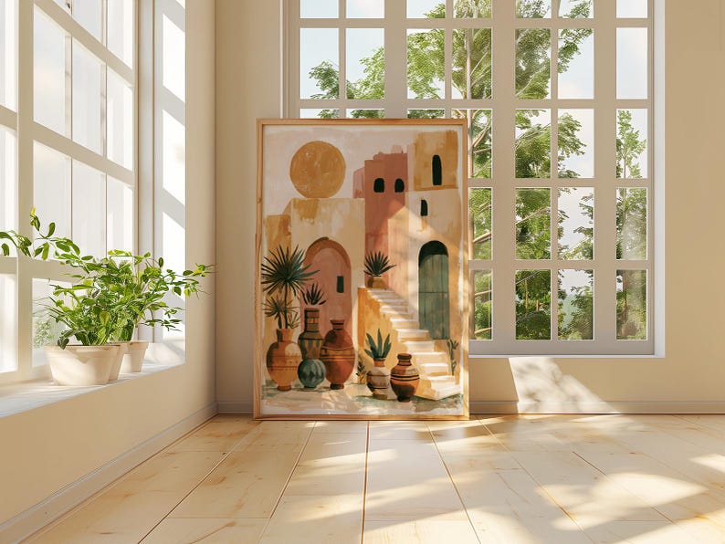 Peut inclure: Une impression d'art encadr&eacute;e repr&eacute;sentant une sc&egrave;ne de village d&eacute;sertique avec un grand soleil, des b&acirc;timents en terre cuite et divers vases. L'&oelig;uvre est expos&eacute;e dans une pi&egrave;ce lumineuse avec une fen&ecirc;tre et des plantes en pot.