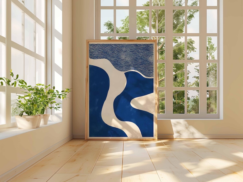Puede incluir: Una impresi&oacute;n art&iacute;stica abstracta enmarcada con formas azules, blancas y beige. La obra de arte se exhibe en una habitaci&oacute;n con una ventana y luz natural. La impresi&oacute;n es rectangular y tiene un marco de madera.