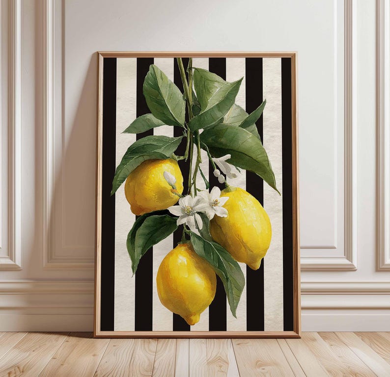 May include: Framed art print featuring a watercolor illustration of lemons with green leaves and white blossoms. The lemons are yellow, set against a black and white striped background. The frame is a light brown color.
