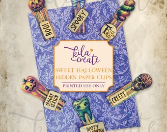 May include: Printable Halloween paper clips with various spooky designs, including a pumpkin, a mummy, a tooth, a skull, and a candy cane. The paper clips are on a purple background with a floral pattern. The text "kila create" is in the center of the image. The text "Sweet Halloween Hidden Paper Clips" is below the text "kila create". The text "Printed Use Only" is below the text "Sweet Halloween Hidden Paper Clips".