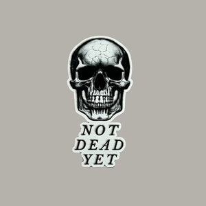 May include: Black and white illustration of a skull with the text "NOT DEAD YET" below it.