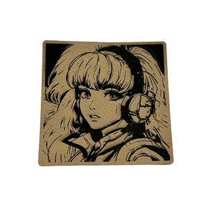 May include: A square sticker featuring a black and tan anime-style illustration of a woman with long hair and headphones. The artwork has a retro aesthetic, with bold lines and a detailed design.