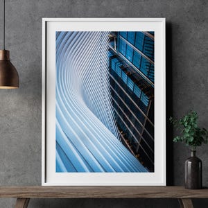 May include: A framed photograph of a modern building with a curved, white facade and a glass exterior. The building is viewed from a low angle, looking up at the curved facade.