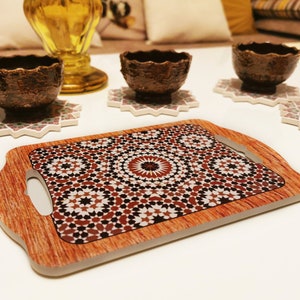 Può includere: Un vassoio di servizio in legno con un motivo geometrico in tonalità di marrone, rosso e bianco. Il vassoio ha un manico su ogni lato ed è perfetto per servire spuntini o bevande.