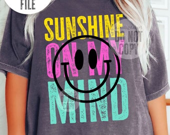 May include: A gray t-shirt with the text "Sunshine on my mind" in pink, yellow, and turquoise. A smiling face graphic is in the center of the text.