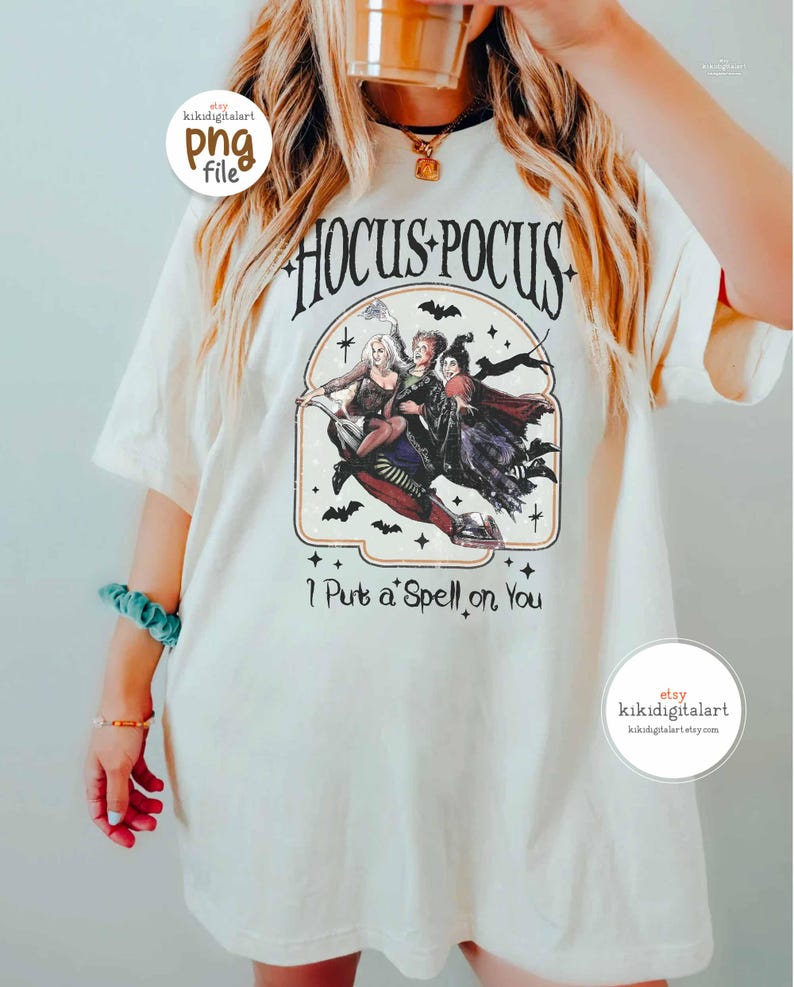 May include: Cream-colored t-shirt featuring a graphic from the movie "Hocus Pocus." The design includes the text "Hocus Pocus" above an illustration of the Sanderson sisters riding a broom. Below the image, the text reads "I Put a Spell on You."