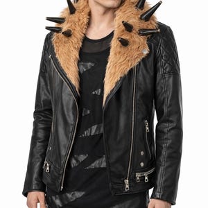 May include: A black leather jacket featuring a large tan faux fur collar adorned with multiple black spikes. The jacket includes silver-tone metal zippers, quilted shoulder detailing, and is worn over a black shirt with diagonal cut-out accents.