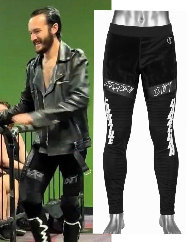 May include: Black pants featuring a wide waistband, ribbed knee panels, and white graphic text on the thighs reading CRASH OUT. The design includes additional white vertical text along the lower legs and a small circular logo on the upper hip.
