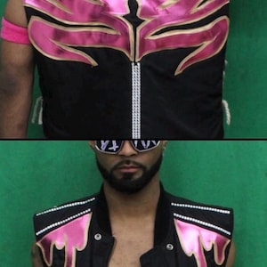 May include: A black sleeveless vest featuring metallic pink flame-like appliques on the chest and back. The garment includes vertical rows of silver rhinestones along the center back and shoulder panels, with a front zipper closure and silver studs.