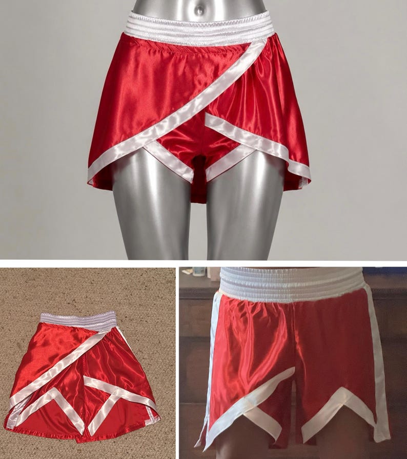 May include: Bright red satin athletic shorts featuring a wide white elastic waistband and white trim detailing along the overlapping front panels. The shorts have a short, flared cut with a smooth, shiny finish and distinct white geometric accents.
