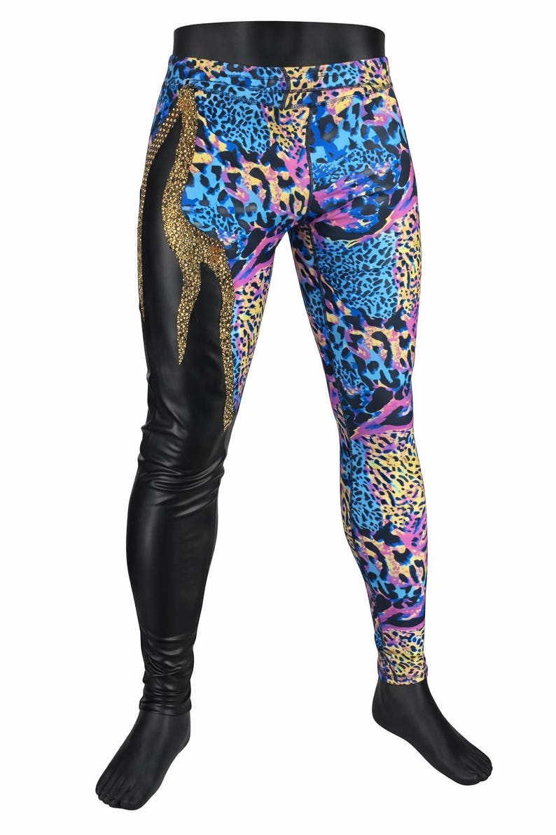 May include: Leggings featuring a split design with one side in solid black and the other in a vibrant blue, purple, and yellow animal print. A vertical panel of gold-toned embellishments separates the two sections along the upper thigh area.