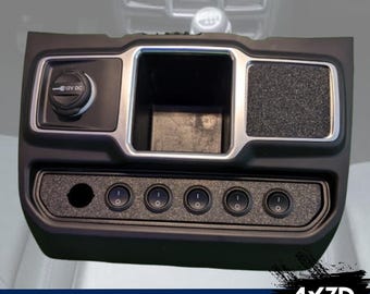 Könnte beinhalten: Schwarzes Kunststoffpanel mit silberner Einfassung und sechs Kippschaltern. Das Panel verfügt über ein kleines Ablagefach und eine 12V-DC-Steckdose.  JL/JT Models 4x3D