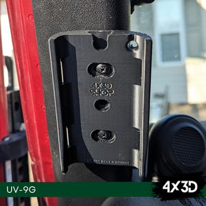 May include: A black plastic phone mount with the text "4x3D SHOP" printed on it. The mount is attached to a red car door.