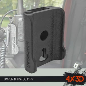 Puede incluir: Un soporte de clip para cinturón de plástico negro impreso en 3D, diseñado para los modelos de radio UV-5R y UV-5G Mini. El soporte presenta una superficie texturizada, una abertura circular central y una ranura en forma de cerradura, con el texto UV5R-MINI.