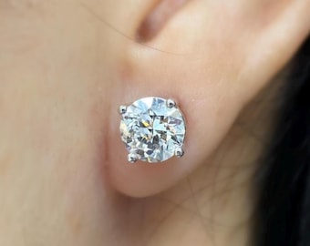 Op de afbeelding: Een close-up van een oor met een grote, ronde, heldere diamant oorbel.