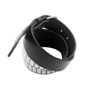 May include: A black leather belt with silver pyramid-shaped studs. The belt is rolled up and the buckle is visible.