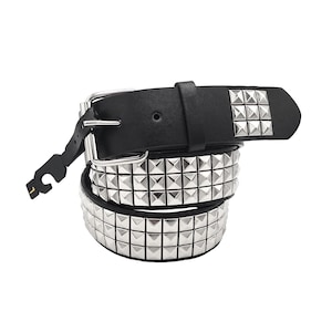 May include: A black leather belt with silver pyramid-shaped studs. The belt is rolled up and the buckle is visible.