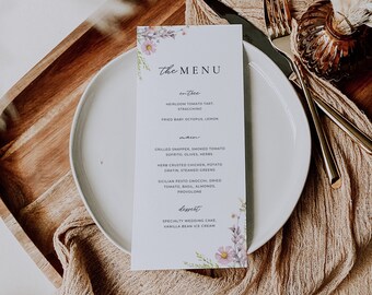 Può includere: Un menu bianco con un design floreale nell'angolo in basso a destra. Il menu è intitolato "The Menu" e elenca le opzioni per antipasto, piatto principale e dessert. L'antipasto è una torta di pomodoro antico, stracchino e polpo fritto con limone. Il piatto principale è branzino grigliato con pomodoro affumicato, sofrito, olive, erbe aromatiche, pollo con crosta di erbe con gratin di patate, verdure al vapore e gnocchi al pesto siciliano con pomodoro secco, basilico, mandorle e provolone. Il dessert è una torta nuziale speciale e gelato alla vaniglia.