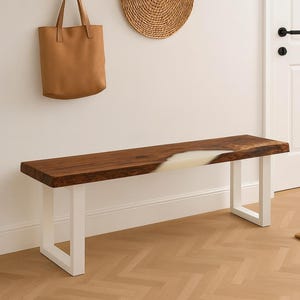 May include: A wooden bench with a live edge and white resin inlay. The bench has white metal legs and is approximately 60 inches long. A brown leather tote bag hangs on the wall above the bench.