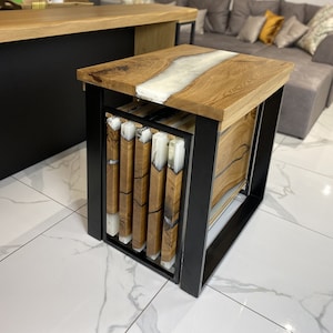 Puede incluir: Mesa auxiliar de madera con estructura de metal negro. La encimera presenta un diseño de río de resina blanca. La mesa mide aproximadamente 50 cm de largo, 50 cm de ancho y 50 cm de alto. Se aprecia la veta de la madera.