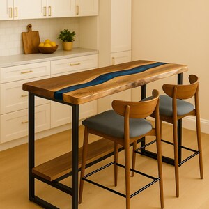 Op de afbeelding: Een rechthoekige houten tafel met een centrale blauwe harsinleg, ondersteund door een zwart metalen frame en een onderste plank, vergezeld door twee houten barkrukken met grijze gestoffeerde zittingen en gebogen rugleuningen.