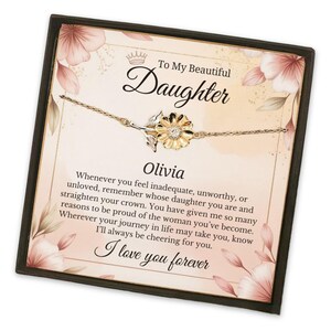May include: A gold and silver sunflower bracelet on a card with the text "To My Beautiful Daughter" and the name "Olivia". The card has a floral design and the words "I love you forever".