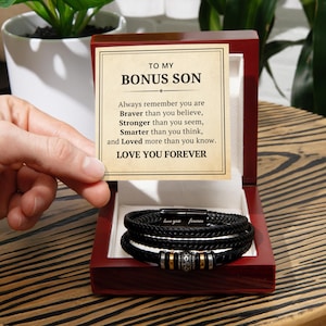 May include: A wooden box with a black leather bracelet inside. The box has a card inside that reads "To My Bonus Son" and a message about being brave, strong, smart, and loved.