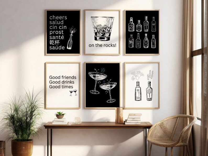 May include: Set of six black and white printable wall art prints with various illustrations of drinks and quotes about drinking. The prints feature a glass of ice, a cocktail glass, a bottle of liquor, and the text "cheers", "salud", "cin cin", "prost", "sant&eacute;", "乾杯", "sa&uacute;de", "on the rocks!", "Good friends", "Good drinks", "Good times".
