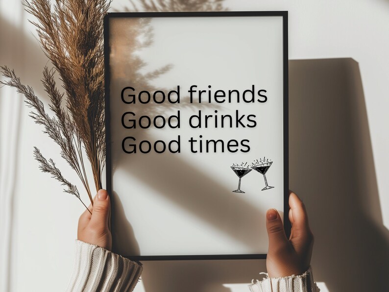 May include: A black framed print with the text "Good friends Good drinks Good times" and a drawing of two martini glasses with a starburst design above each glass.