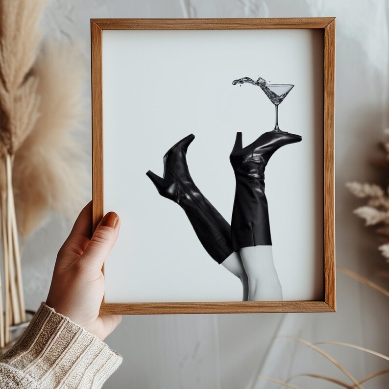 K&ouml;nnte beinhalten: Schwarzwei&szlig;foto von einem Paar schwarzer Stiefel mit Abs&auml;tzen, auf denen ein Martini-Glas balanciert.