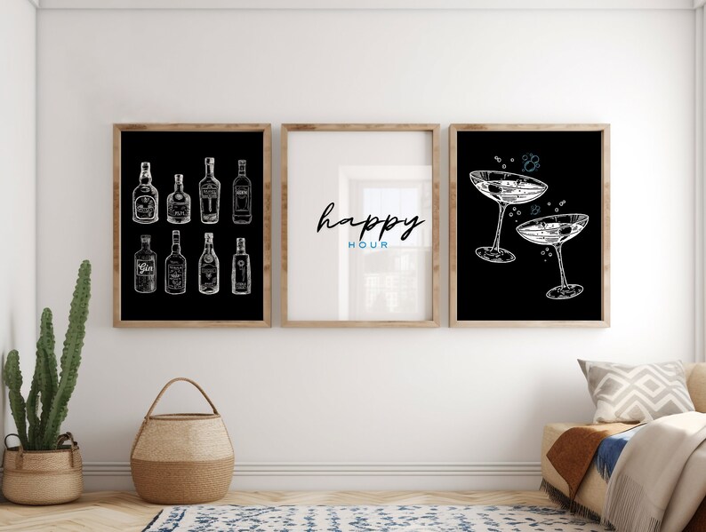 May include: Three black and white framed prints with a minimalist design. The left print features a collection of liquor bottles, the middle print says "happy hour" in cursive, and the right print shows two champagne flutes.