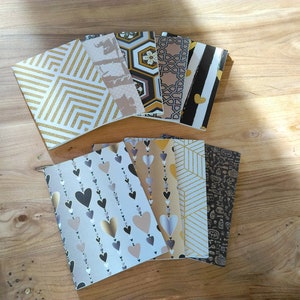 Può includere: Un set di otto piccoli quaderni con diversi disegni geometrici e motivi. Le copertine sono un mix di nero, bianco, oro e argento.