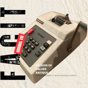 Puede incluir: Una calculadora Facit vintage blanca con un teclado negro y un soporte para rollo de papel. La calculadora está en funcionamiento y tiene el texto "ORDINAL VIII" en el lateral.