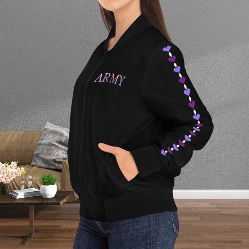 May include: Black bomber jacket with the word "ARMY" embroidered in purple on the chest. The left sleeve features a line of purple and white hearts. The jacket has a zipper closure and two pockets.