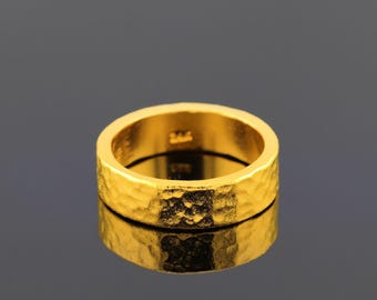 May include: A gold ring with a hammered texture. The ring is thick and has a wide band.