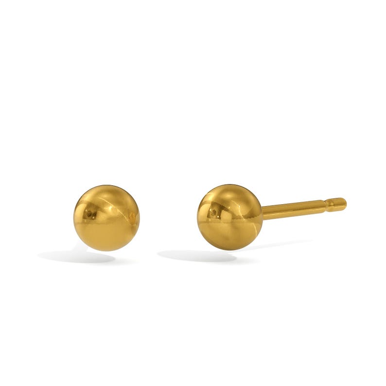 Pu&ograve; includere: Un paio di orecchini a lobo a sfera color oro. Un orecchino &egrave; mostrato con il perno, l'altro &egrave; separato. Gli orecchini sono rotondi e lucenti, riflettendo la luce. Lo sfondo &egrave; bianco.